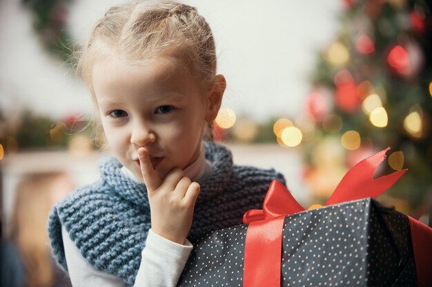 Concepto de Navidad una niña presiona un dedo a sus labios