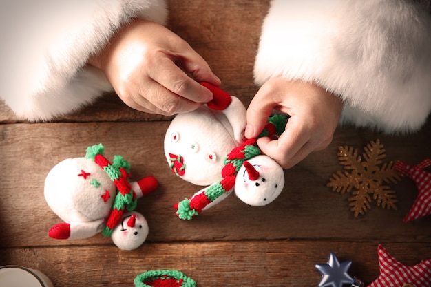 Concepto de navidad. Santa Claus hace juguetes de cerca. Adornos navideños en mesa de madera.