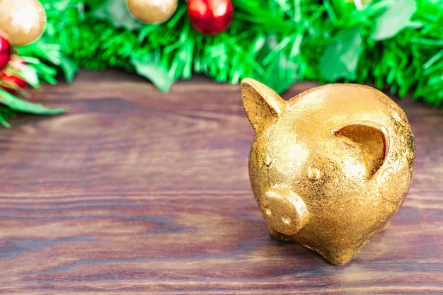 Concepto de Navidad - símbolo del año del cerdo dorado se encuentra en una mesa de madera con fondo de ramas de árboles de Navidad