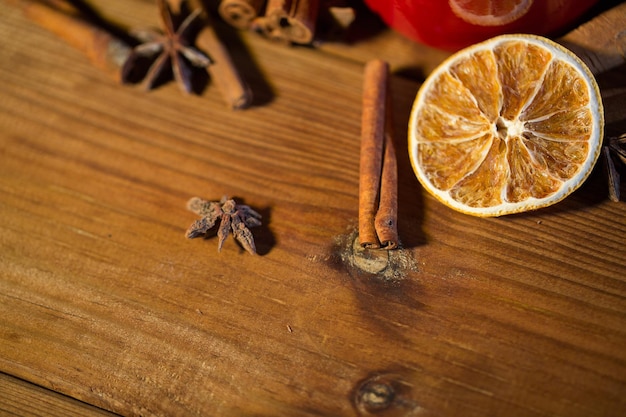 concepto de navidad, vacaciones, cocina y especias - cierre de canela, anís y naranja seca en tablero de madera