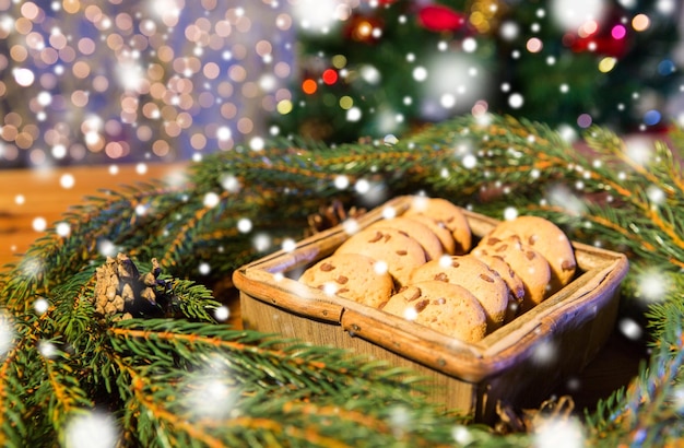 concepto de navidad, vacaciones, comida y horneado - primer plano de la corona de navidad de abeto verde natural y galletas de avena en una caja de madera en la mesa sobre las luces