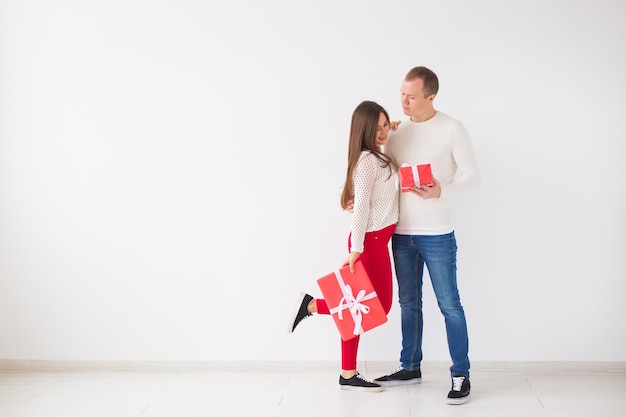 Concepto de Navidad, vacaciones, día de San Valentín y cumpleaños: el hombre y la mujer felices tienen cajas con regalos sobre fondo blanco con espacio de copia.