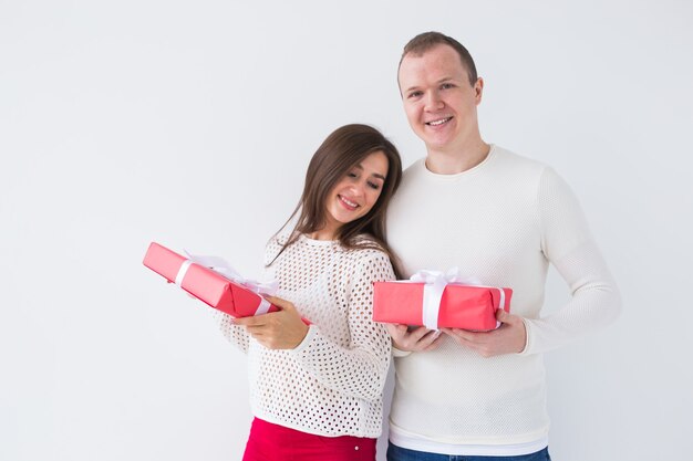 Foto concepto de navidad, vacaciones, día de san valentín y cumpleaños: el hombre y la mujer felices tienen cajas con regalos sobre fondo blanco.