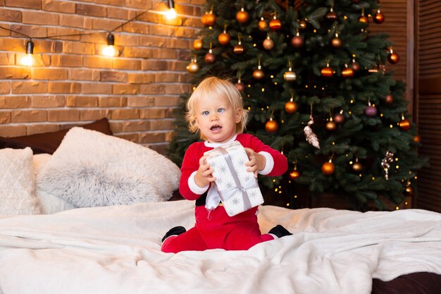 Concepto de Navidad, vacaciones y infancia - niño sonriente con caja de regalo en casa