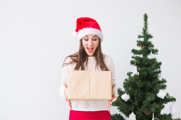 Concepto de Navidad y vacaciones - mujer joven con sombrero de santa con caja de regalo