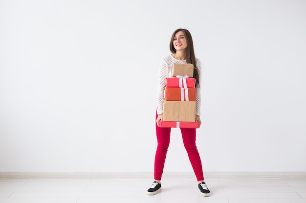Concepto de Navidad y vacaciones - mujer joven sosteniendo una pila de cajas de regalo sobre fondo blanco con espacio de copia