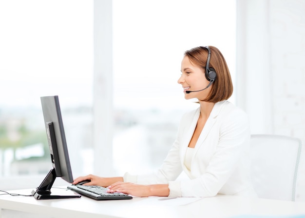 concepto de negocio, comunicación, tecnología y centro de llamadas: operadora de línea de ayuda femenina amigable con auriculares y centro de llamadas de computadora