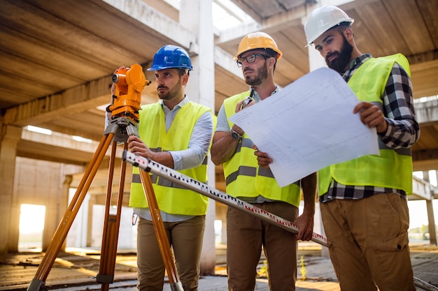 Foto concepto de negocio, construcción, trabajo en equipo y personas. grupo de ingenieros y arquitectos en cascos con planos en el sitio de construcción