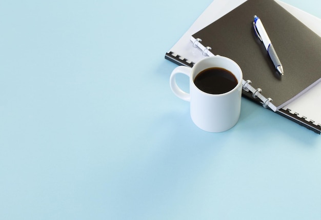 concepto de negocio con cuadernos, bolígrafo y taza de café sobre fondo azul