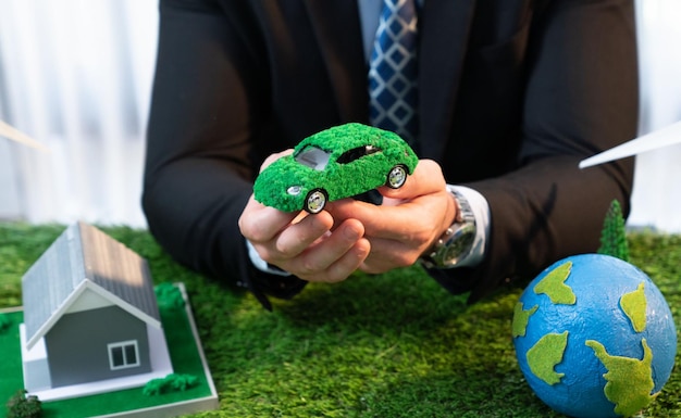 El concepto de negocio ecológico y salvamento de la Tierra mostrado por un empresario o CEO sosteniendo un globo de papel en la oficina con una maqueta ecológica para promover la reducción de CO2 y huella de carbono para un futuro más verde