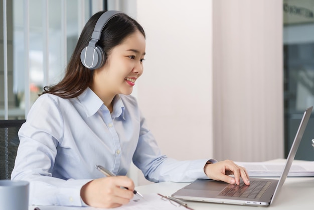 Concepto de negocio Empresaria en auriculares para reunirse en videoconferencia y tomar notas en papel