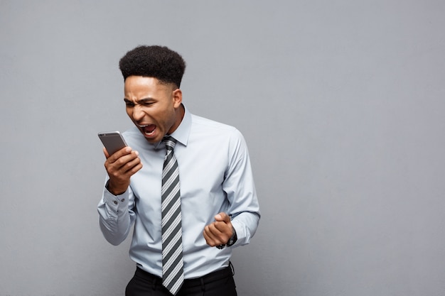Concepto de negocio - empresario afroamericano estresante gritando y gritando en el teléfono móvil.