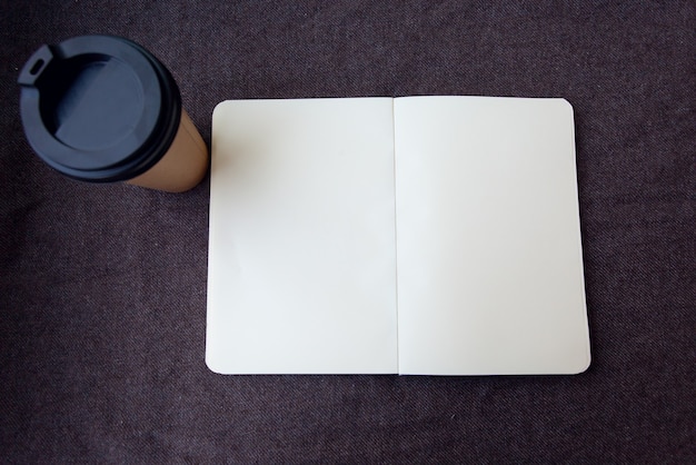 Concepto de negocio, estilo de vida, comida y café: lápiz, cuaderno y taza de café de papel sobre un fondo de tela marrón