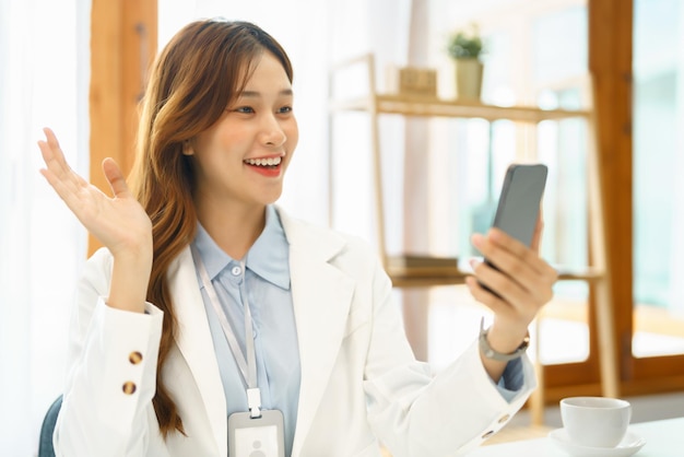 Concepto de negocio exitoso La empresaria usa videollamada en un teléfono inteligente para saludar con un colega