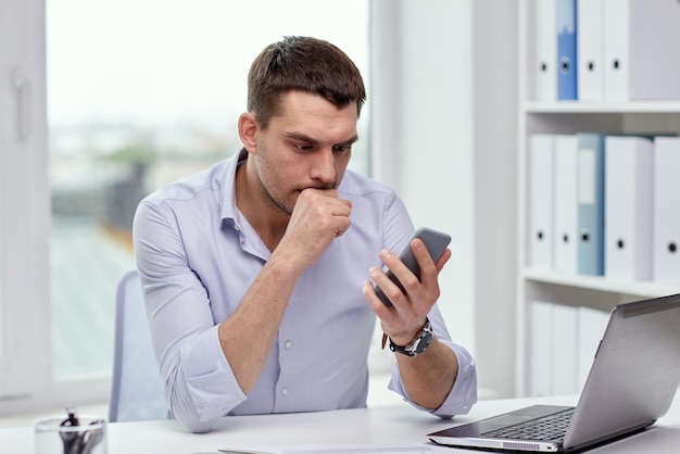 concepto de negocio, fecha límite, personas y tecnología - hombre de negocios con teléfono inteligente y computadora portátil en la oficina