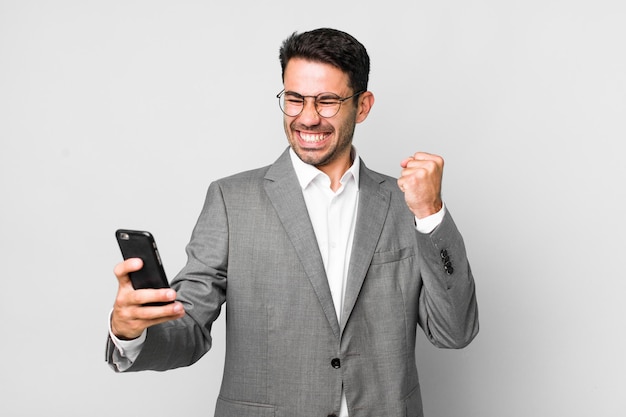 Concepto de negocio de hombre hispano guapo adulto joven con un teléfono móvil