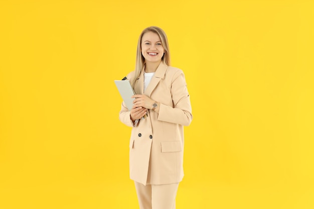 Concepto de negocio con una joven y atractiva mujer de negocios de fondo amarillo