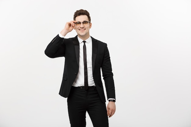 Concepto de negocio: joven empresario guapo con gafas sosteniendo la mano en el bolsillo aislado sobre fondo blanco.