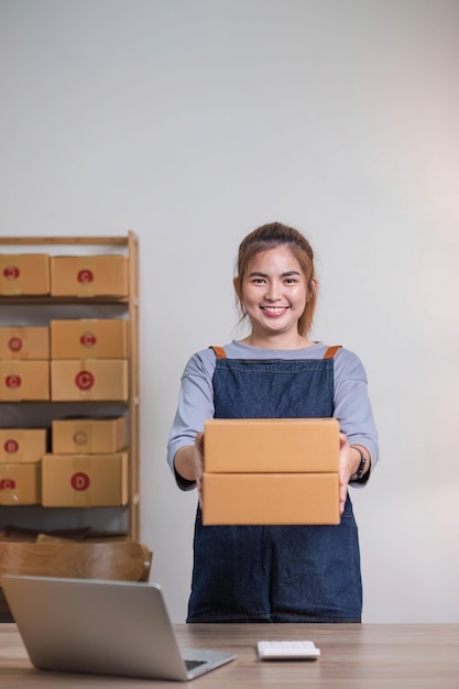 Concepto de negocio en línea Mujeres de negocios asiáticas sostienen cajas de paquetes de productos para su entrega al cliente