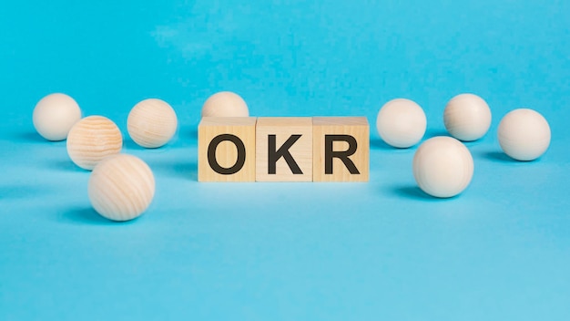 Concepto de negocio en la mesa azul bolas de madera y cubos de madera con la inscripción Objetivos OKR y resultados clave