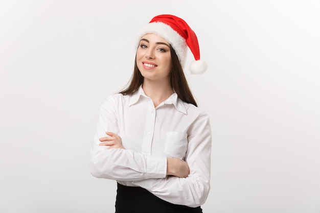 Concepto de negocio mujer de negocios caucásica moderna en tema de Navidad brazo cruzado posando sobre pared blanca con espacio de copia