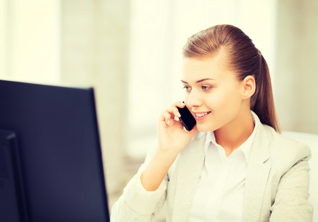 concepto de negocio - mujer de negocios sonriente con teléfono inteligente en la oficina