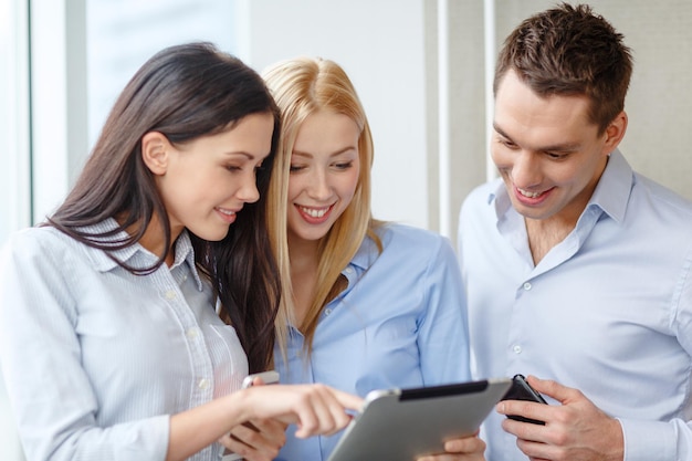 Concepto de negocio y oficina: equipo de negocios sonriente que trabaja con tabletas y teléfonos inteligentes en la oficina