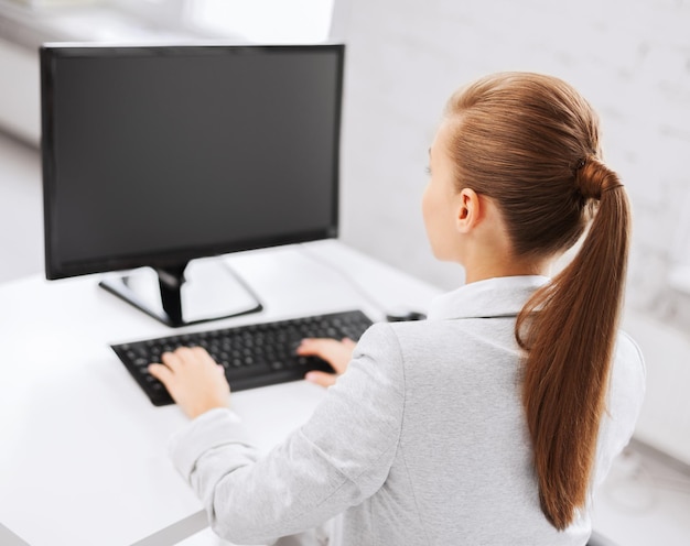 Concepto de negocio, oficina, escuela y educación - empresaria en computadora con pantalla en blanco en la oficina