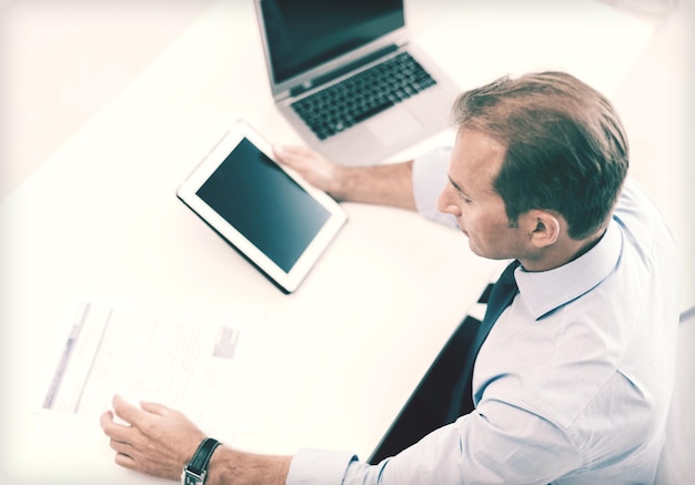 concepto de negocio, oficina, escuela y educación - empresario con tablet pc y papeles en la oficina