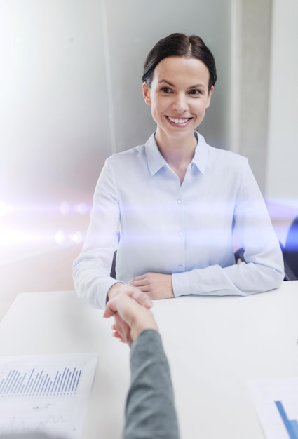 Foto concepto de negocio y oficina - mujer de negocios sonriente estrechando la mano en la oficina