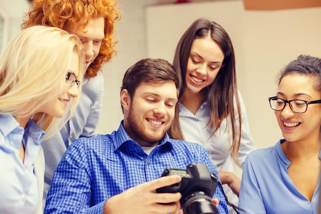 concepto de negocio, oficina y puesta en marcha - equipo creativo sonriente con cámara fotográfica trabajando en la oficina