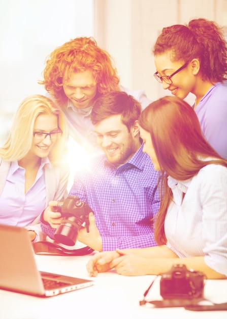 Foto concepto de negocio, oficina y puesta en marcha: equipo creativo sonriente con computadora portátil y fotógrafos que trabajan en la oficina