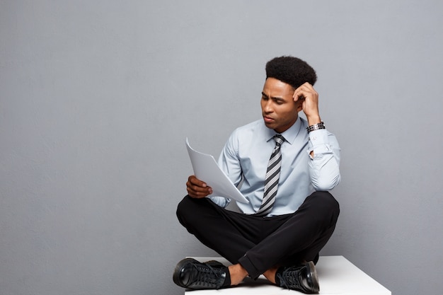 Concepto del negocio - papeleo serio joven hermoso de la lectura profesional del hombre de negocios del afroamericano.