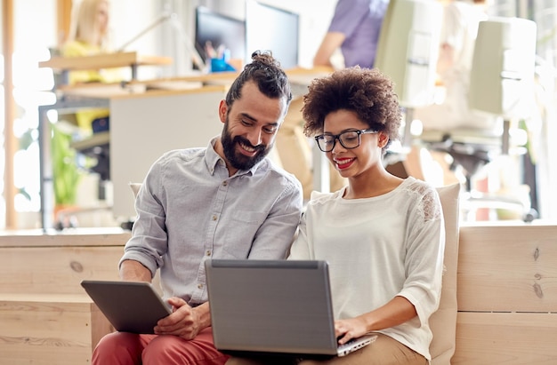 concepto de negocio, puesta en marcha y personas: equipo creativo feliz con computadora portátil y tableta en la oficina