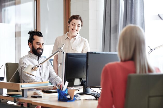 concepto de negocio, puesta en marcha y personas - feliz equipo creativo con computadoras en la oficina