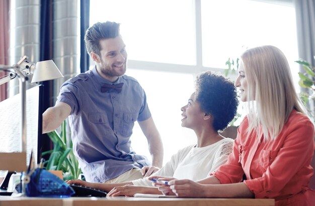 concepto de negocio, puesta en marcha y personas - feliz red de equipos creativos con computadora en la oficina