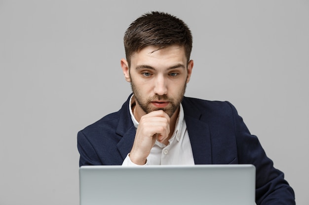 Concepto de negocio - Retrato apuesto hombre de negocios estresante en choque de traje mirando delante de la computadora portátil en la oficina de trabajo. Fondo blanco.