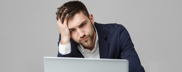 Concepto de negocio retrato apuesto hombre de negocios serio en traje mirando portátil fondo blanco.