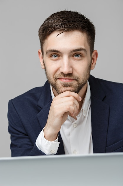 Concepto de negocio - Retrato apuesto hombre de negocios serio en traje mirando el trabajo en la computadora portátil. Fondo blanco.