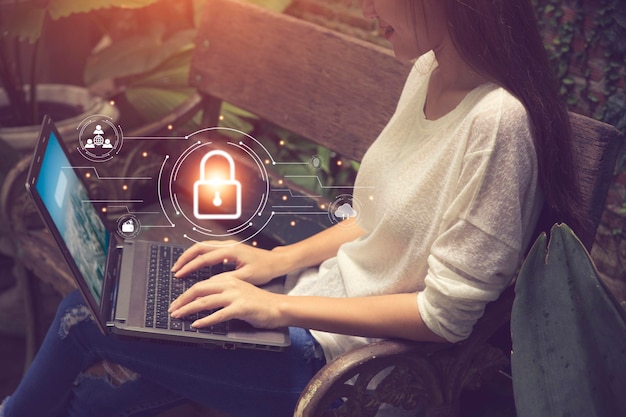 Concepto de negocio, tecnología, internet y redes. empresaria trabajando en su computadora portátil en casa, seleccione el icono de seguridad en la pantalla virtual.