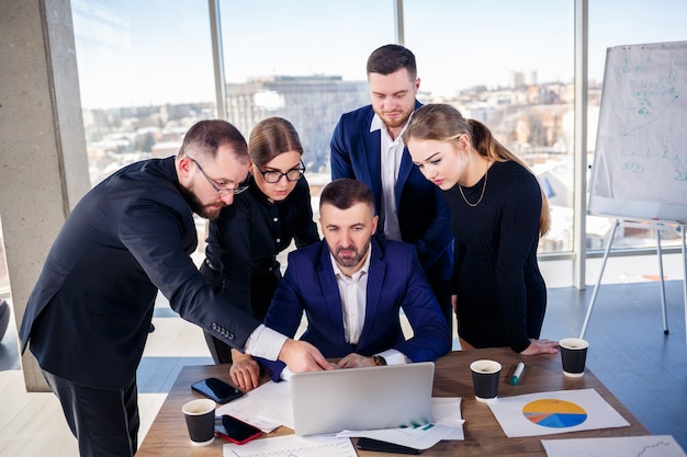 Concepto de negocio, tecnología y oficina - equipo de negocios feliz con computadoras portátiles, documentos y café. Reunión antes del inicio de la jornada laboral para discutir un plan de negocios