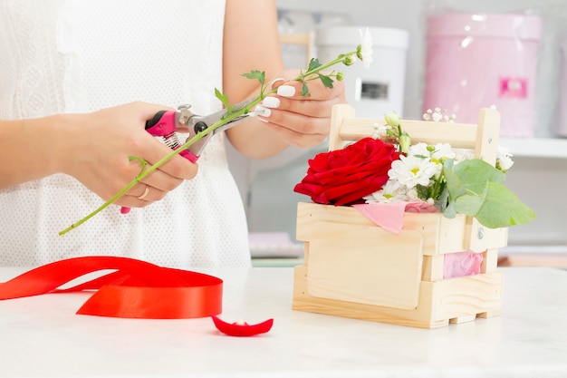 Concepto de negocio, venta y floristería - cerca de mujer floristería sosteniendo ramo en la tienda de flores. Tonos suaves de flores frescas de primavera.