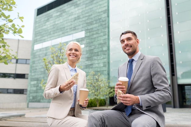 concepto de negocios, asociación, comida, bebidas y personas - hombres de negocios sonrientes con vasos de papel parados sobre el edificio de oficinas