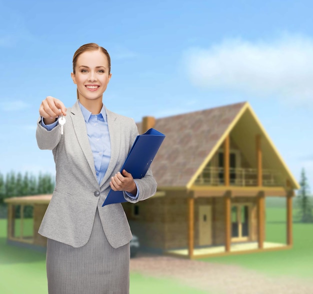 Foto concepto de negocios, bienes raíces, banca y oficina - mujer de negocios sonriente con carpeta y llaves