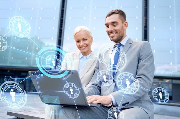 concepto de negocios, comunicación, tecnología y personas: empresarios sonrientes que trabajan con computadora portátil y proyección de red en la calle de la ciudad