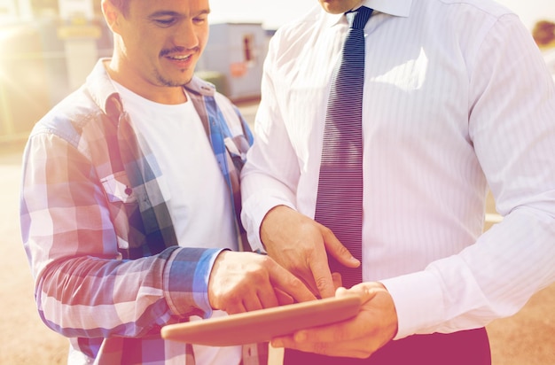 concepto de negocios, construcción, construcción, tecnología y personas - primer plano de un constructor y un hombre de negocios con una tableta y una computadora al aire libre