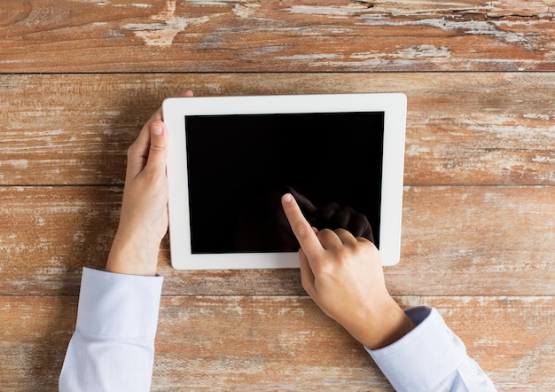 concepto de negocios, educación, personas y tecnología: cierre de manos femeninas que señalan con el dedo a la pantalla en blanco negra de la computadora de la tableta en la mesa