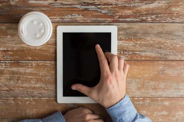 concepto de negocios, educación, personas y tecnología: cierre de manos masculinas con computadora de tablet pc y taza de papel de café en la mesa