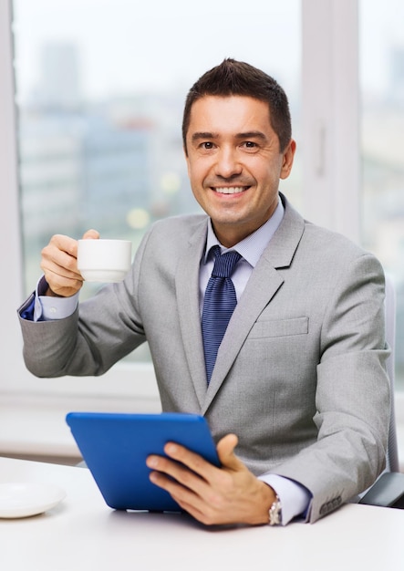 Foto concepto de negocios, educación, personas y tecnología - hombre de negocios sonriente con computadora de tablet pc y café en la oficina