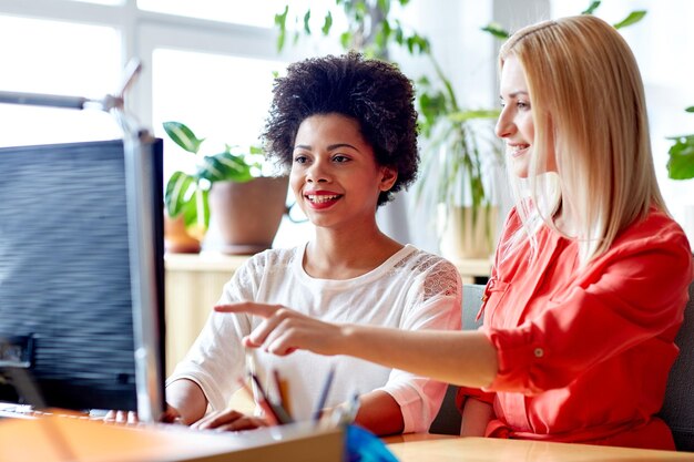 concepto de negocios, educación, puesta en marcha y personas: mujeres felices o estudiantes con computadora en la oficina